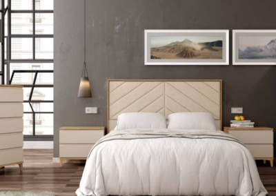Dormitorio con cabecero tapizado hill en color nogal combinado con perla. Mesitas con patas piramidales. Tapizado sand.